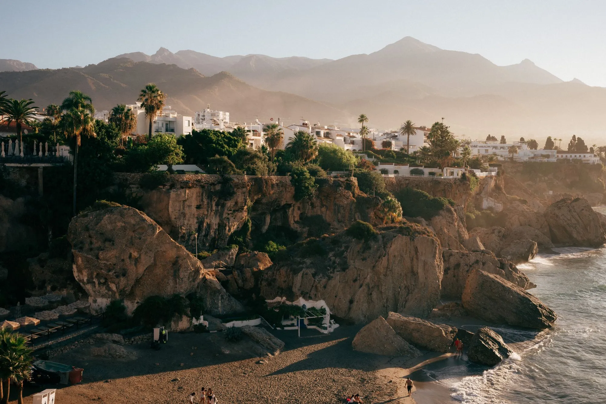 De kust van Nerja met palmen en bergen in het ochtendlicht